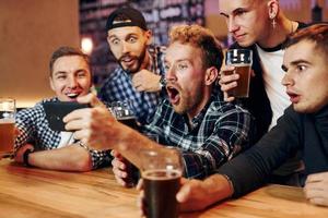 utilise le téléphone. groupe de personnes ensemble à l'intérieur dans le pub s'amuser le week-end photo