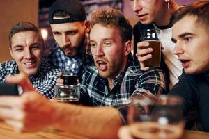 utilise le téléphone. groupe de personnes ensemble à l'intérieur dans le pub s'amuser le week-end photo