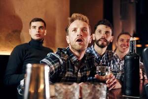 des gens expressifs qui regardent le football. groupe de personnes ensemble à l'intérieur dans le pub s'amuser le week-end photo