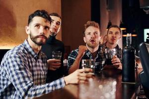 des gens expressifs qui regardent le football. groupe de personnes ensemble à l'intérieur dans le pub s'amuser le week-end photo