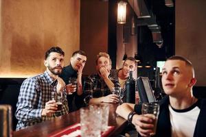 des gens expressifs qui regardent le football. groupe de personnes ensemble à l'intérieur dans le pub s'amuser le week-end photo