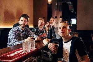 des gens expressifs qui regardent le football. groupe de personnes ensemble à l'intérieur dans le pub s'amuser le week-end photo