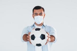 fan de football avec ballon de football. jeune bel homme debout à l'intérieur sur fond blanc photo