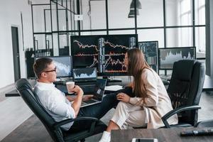 la femme et l'homme ont une conversation. l'équipe d'agents de change travaille dans un bureau moderne avec de nombreux écrans d'affichage photo