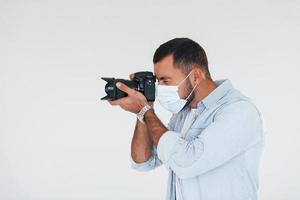 avec caméra professionnelle. jeune bel homme debout à l'intérieur sur fond blanc photo