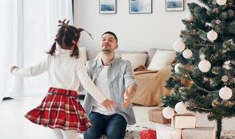 petite fille court vers son père. fête le nouvel an ensemble à la maison photo