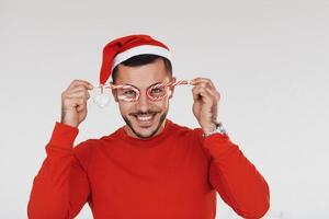 avec des bonbons. jeune bel homme en vêtements de nouvel an debout à l'intérieur sur fond blanc photo