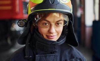 vue rapprochée. femme pompier en uniforme de protection debout près du camion photo