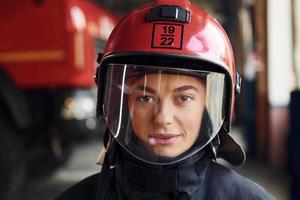 vue rapprochée. femme pompier en uniforme de protection debout près du camion photo