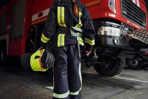 vue rapprochée. femme pompier en uniforme de protection debout près du camion photo