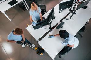 vue de dessus. un groupe de travailleurs nettoie un bureau moderne ensemble pendant la journée photo