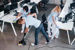 concentré au travail. un groupe de travailleurs nettoie un bureau moderne ensemble pendant la journée photo