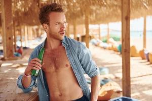 montre le corps. jeune homme européen passe des vacances et profite de temps libre sur la plage de la mer photo