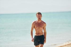 eau claire. jeune homme européen passe des vacances et profite de temps libre sur la plage de la mer photo