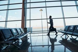 jeune homme en tenue de soirée est dans un aéroport moderne. conception de vacances photo