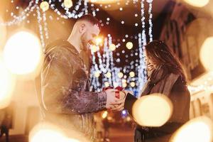 contient une boîte-cadeau. heureux couple multiracial ensemble à l'extérieur dans la ville pour célébrer le nouvel an photo