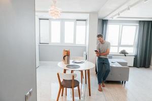 un jeune homme en vêtements décontractés contrôle à l'intérieur la technologie de la maison intelligente photo