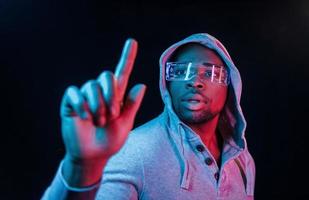 dans des lunettes spéciales. éclairage néon futuriste. jeune homme afro-américain dans le studio photo