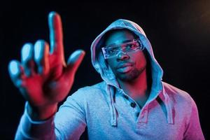 dans des lunettes spéciales. éclairage néon futuriste. jeune homme afro-américain dans le studio photo
