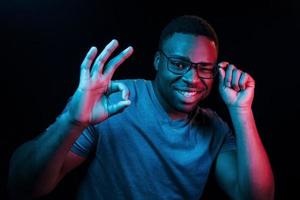 expression faciale. éclairage néon futuriste. jeune homme afro-américain dans le studio photo