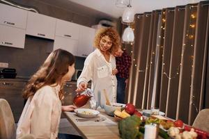 une famille heureuse de mère, fille et fils est dans la cuisine le soir photo