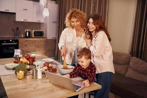 des gens joyeux ayant un week-end heureux. la famille de la mère, de la fille et du fils est dans la cuisine le soir photo