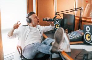 parle et utilise le micro. le jeune homme est à l'intérieur dans le studio de radio est occupé par la diffusion photo