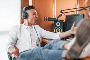 parle et utilise le micro. le jeune homme est à l'intérieur dans le studio de radio est occupé par la diffusion photo