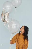 tient des ballons. bonne petite fille debout et s'amuser à l'intérieur à la fête d'anniversaire photo