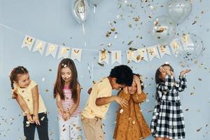 ballons et confettis. les enfants célébrant la fête d'anniversaire à l'intérieur s'amusent ensemble photo