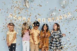 ballons et confettis. les enfants célébrant la fête d'anniversaire à l'intérieur s'amusent ensemble photo