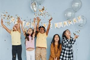 ballons et confettis. les enfants célébrant la fête d'anniversaire à l'intérieur s'amusent ensemble photo