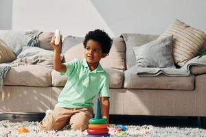 un enfant afro-américain joue avec des jouets à l'intérieur près du lit à la maison photo