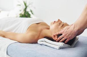 massage crânien. une jeune femme est allongée quand un homme lui fait une procédure au spa
