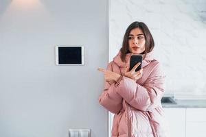 Contrôle du climat. la jeune femme est à l'intérieur dans la chambre de la maison intelligente pendant la journée photo