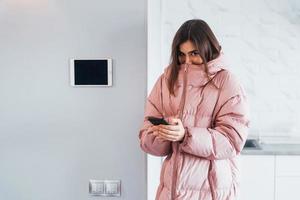 Contrôle du climat. la jeune femme est à l'intérieur dans la chambre de la maison intelligente pendant la journée photo