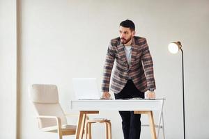 travaille au bureau. jeune homme d'affaires élégant en costume à l'intérieur. conception du succès photo