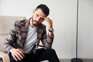 est assis sur la chaise. jeune homme d'affaires élégant en costume à l'intérieur. conception du succès photo