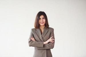 jeune femme en vêtements formels est debout sur fond blanc dans le studio photo