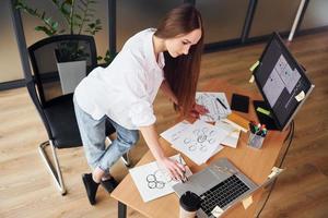 journée chargée. jeune femme adulte en vêtements formels est à l'intérieur au bureau photo