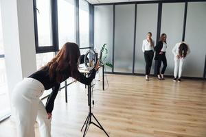 coulisses de la séance photo. groupe de femmes adultes qui, dans des vêtements formels, sont à l'intérieur au bureau ensemble photo