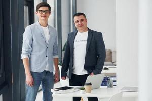 jeune homme avec un homme adulte debout à l'intérieur du bureau ensemble photo