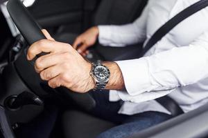 jeune homme en chemise blanche est assis à l'intérieur d'une nouvelle automobile moderne photo