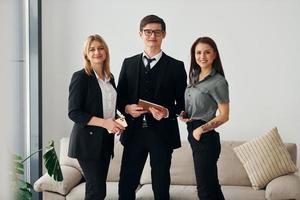 jeune homme et deux femmes en vêtements officiels formels ensemble à l'intérieur photo