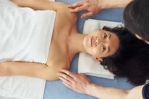 vue de dessus. jeune femme est allongée quand un homme fait un massage de son corps au spa photo