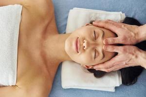 massage crânien. une jeune femme est allongée quand un homme lui fait une procédure au spa