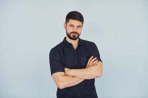 Homme sérieux en chemise debout à l'intérieur sur fond blanc photo