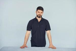 Homme sérieux en chemise debout à l'intérieur sur fond blanc photo