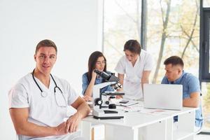 à l'aide d'un microscope. groupe de jeunes médecins travaille ensemble dans le bureau moderne photo