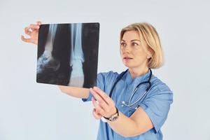 tient la radiographie. femme médecin professionnelle d'âge moyen en uniforme et avec stéthoscope photo